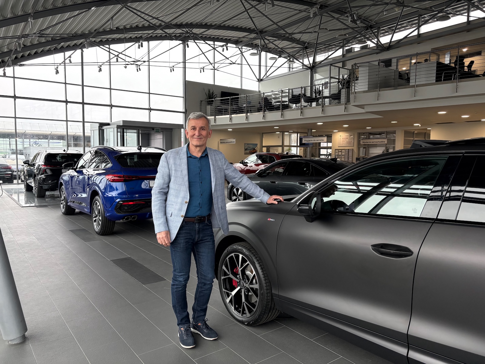 Krzysztof stoi przy Audi A5 w salonie samochodowym